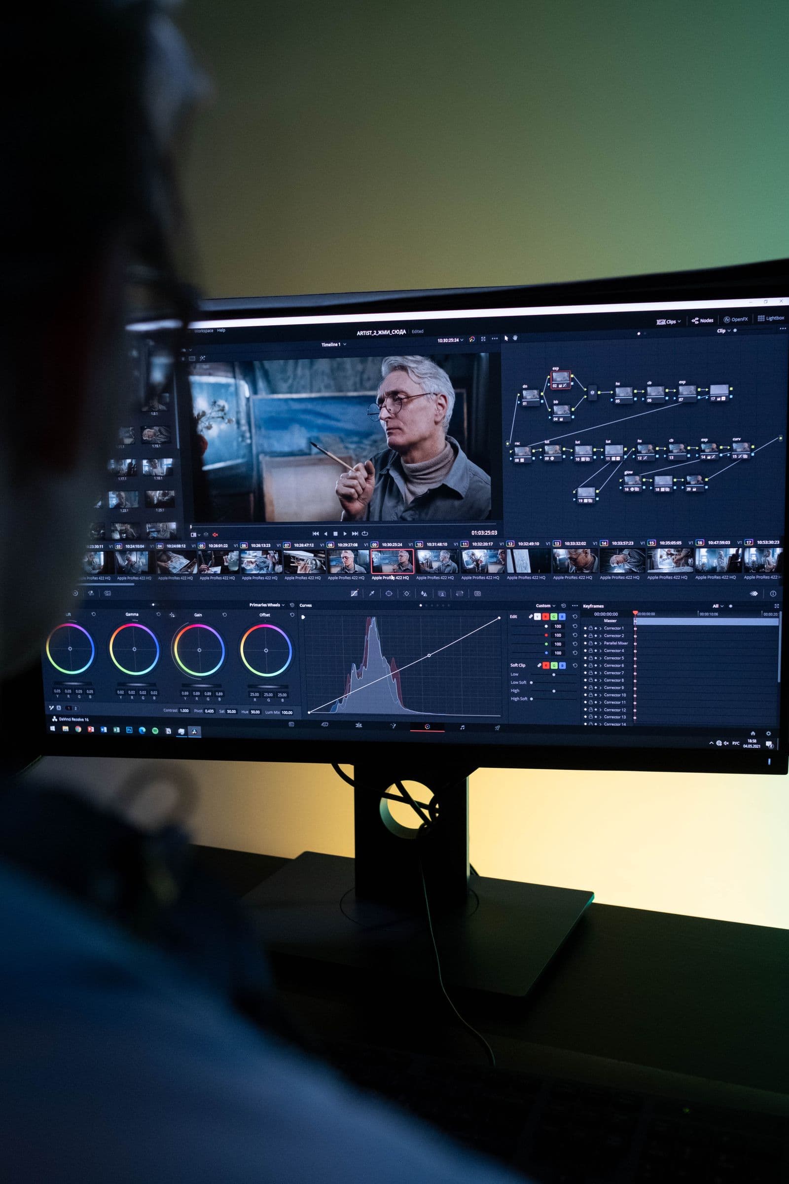 Personne de dos retouchant des images sur un grand écran dans un espace de post-production